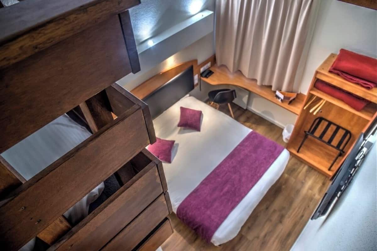 Una habitación de hotel compacta con cama, escritorio y silla.