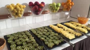 Un bufé con diversas frutas y plátanos en rodajas dispuestas en bandejas.