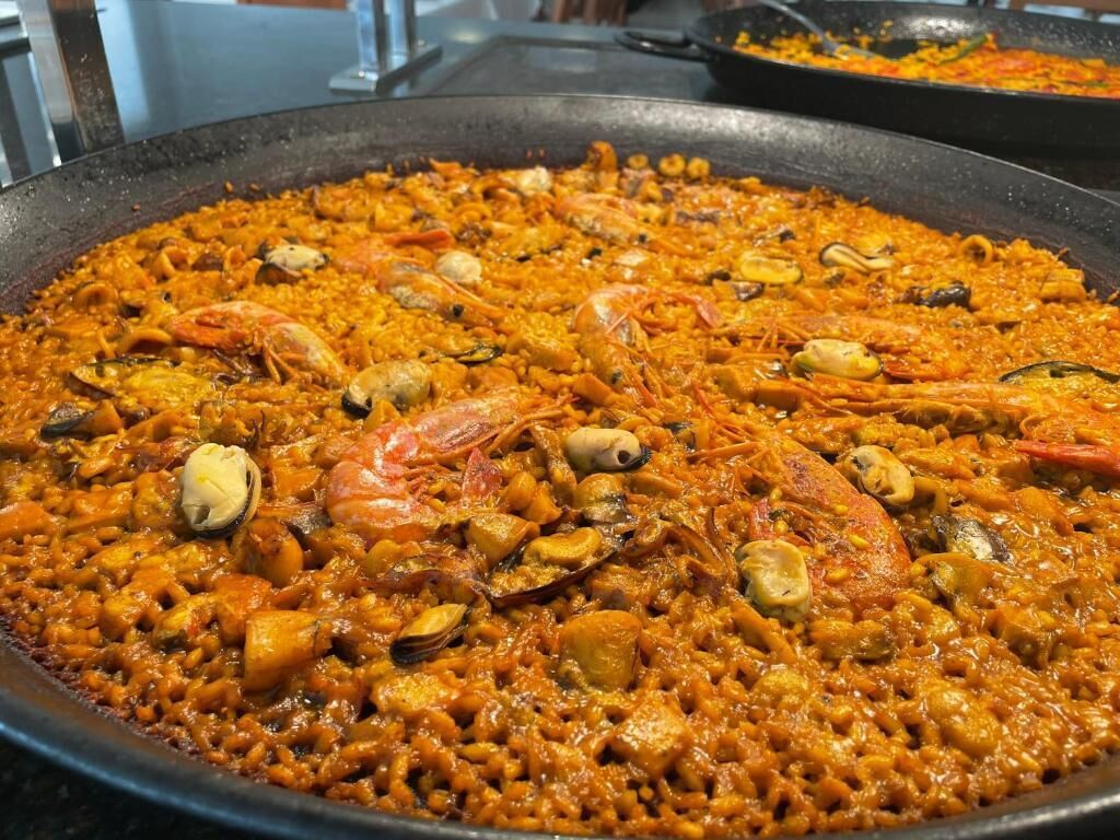 A large pan of seafood paella with shrimp and clams.