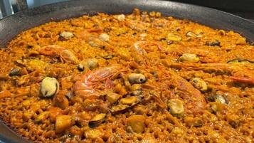 A large pan of seafood paella with shrimp and clams.