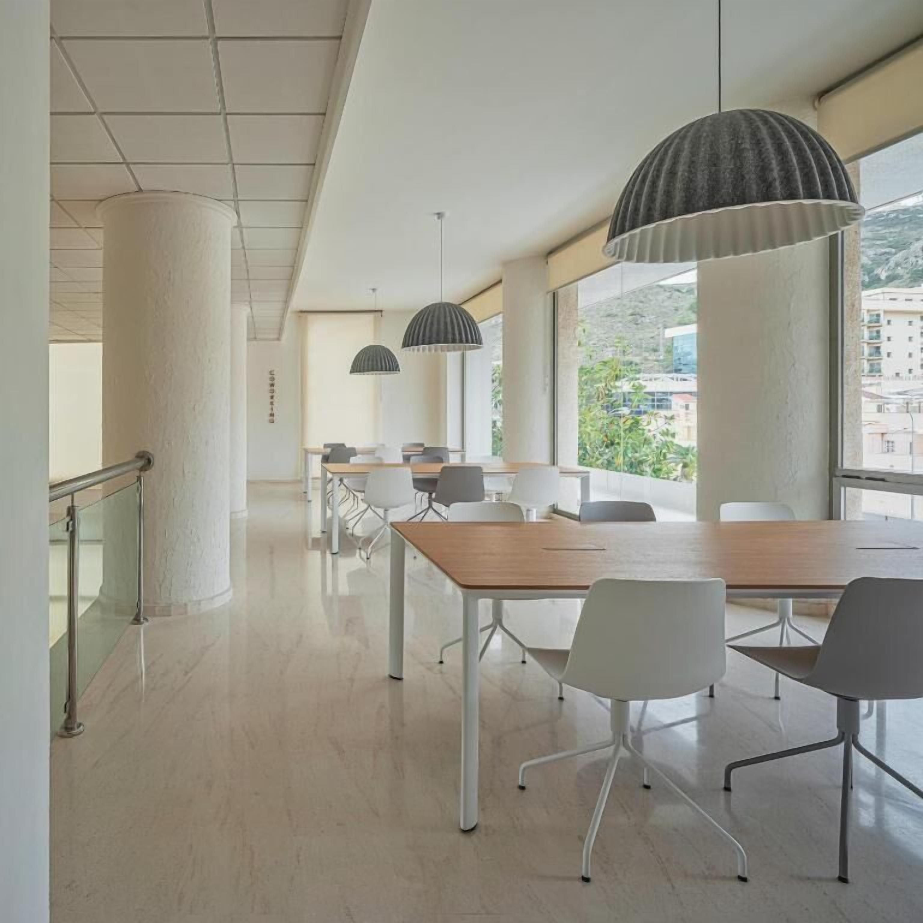 A modern conference room with a long table, white chairs, and pendant lighting.
