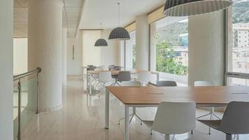A modern conference room with a long table, white chairs, and pendant lighting.