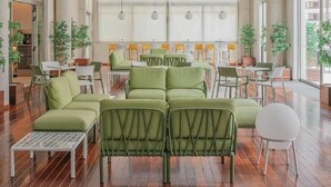 A spacious indoor area with green seating, a ceiling fan, and large windows.
