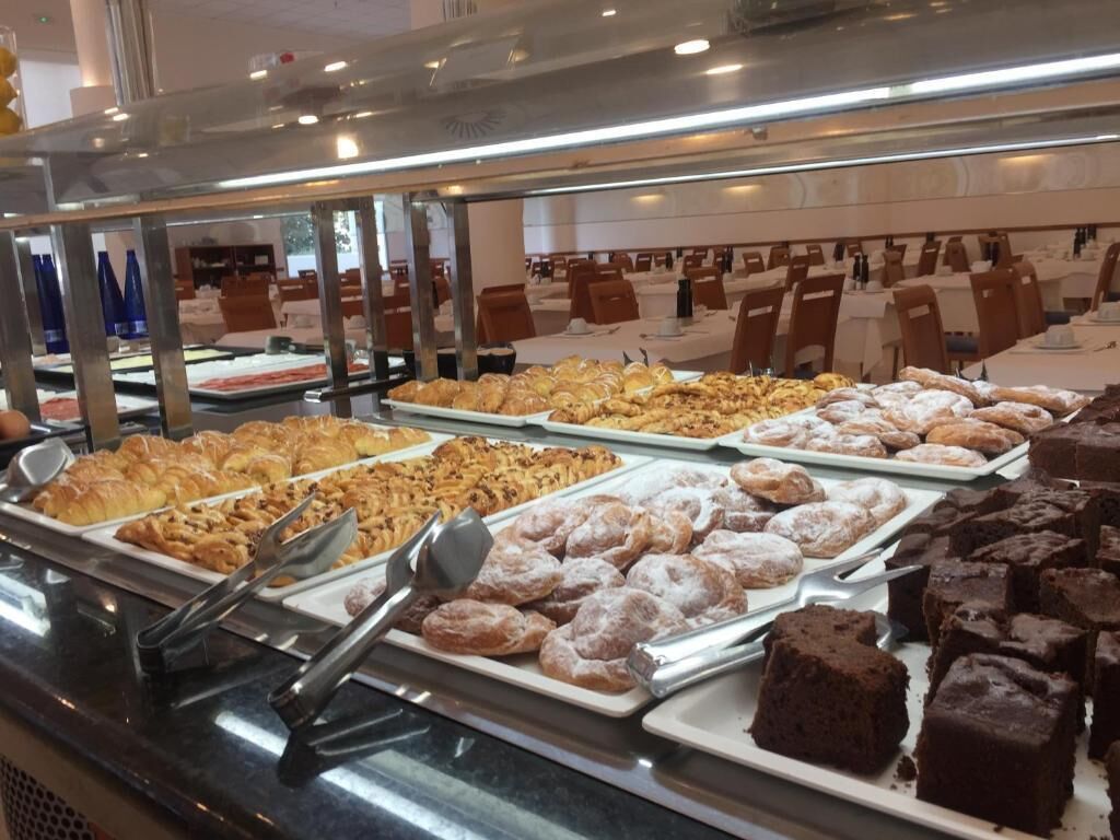 A buffet with various baked goods including pastries, donuts, and brownies.