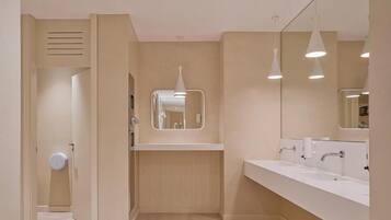 Een moderne badkamer met een lange wastafel, een grote spiegel en inbouwspots.