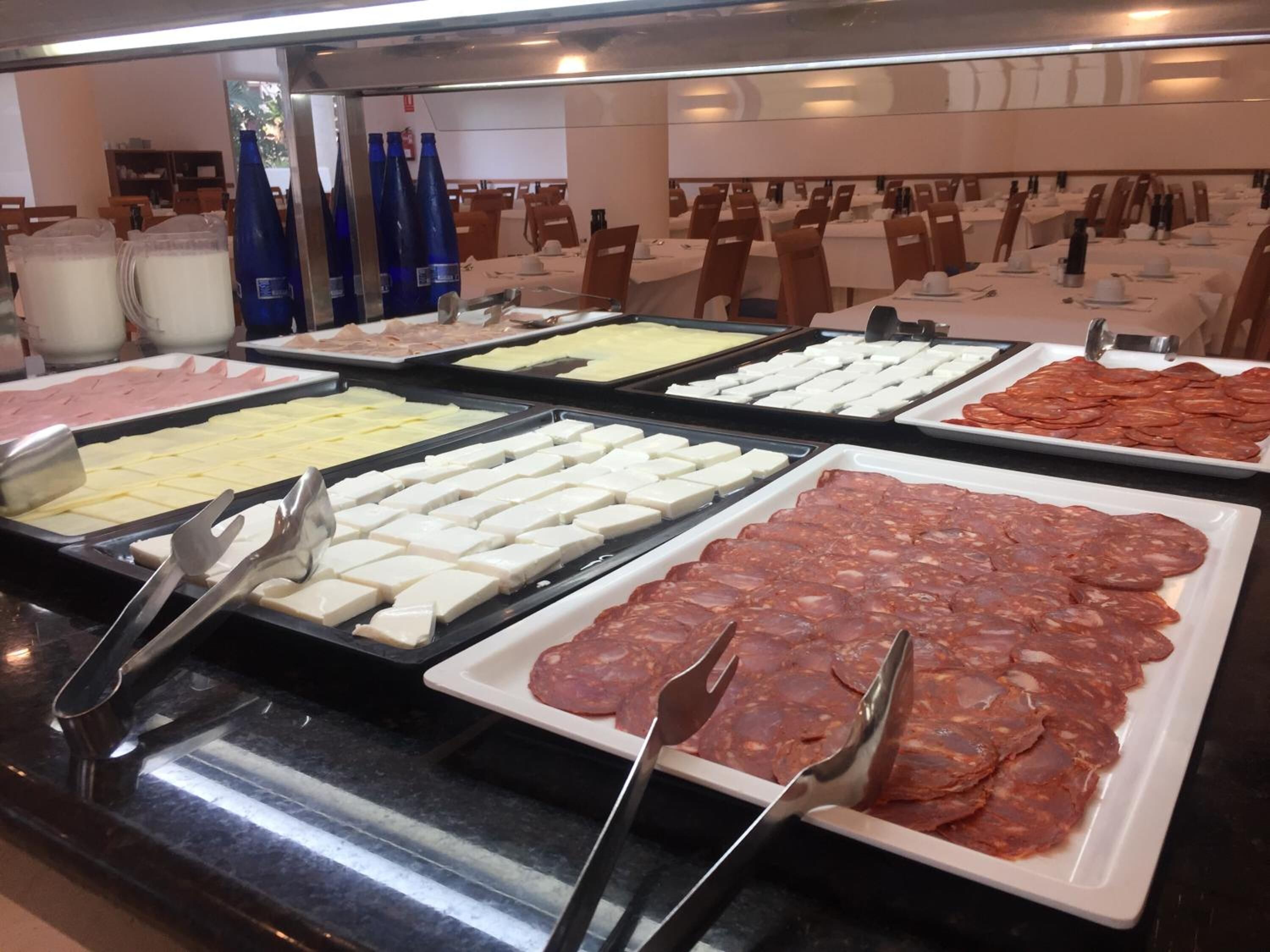 Un bufé con diversas opciones de comida, incluyendo carnes, quesos y otros platos preparados.