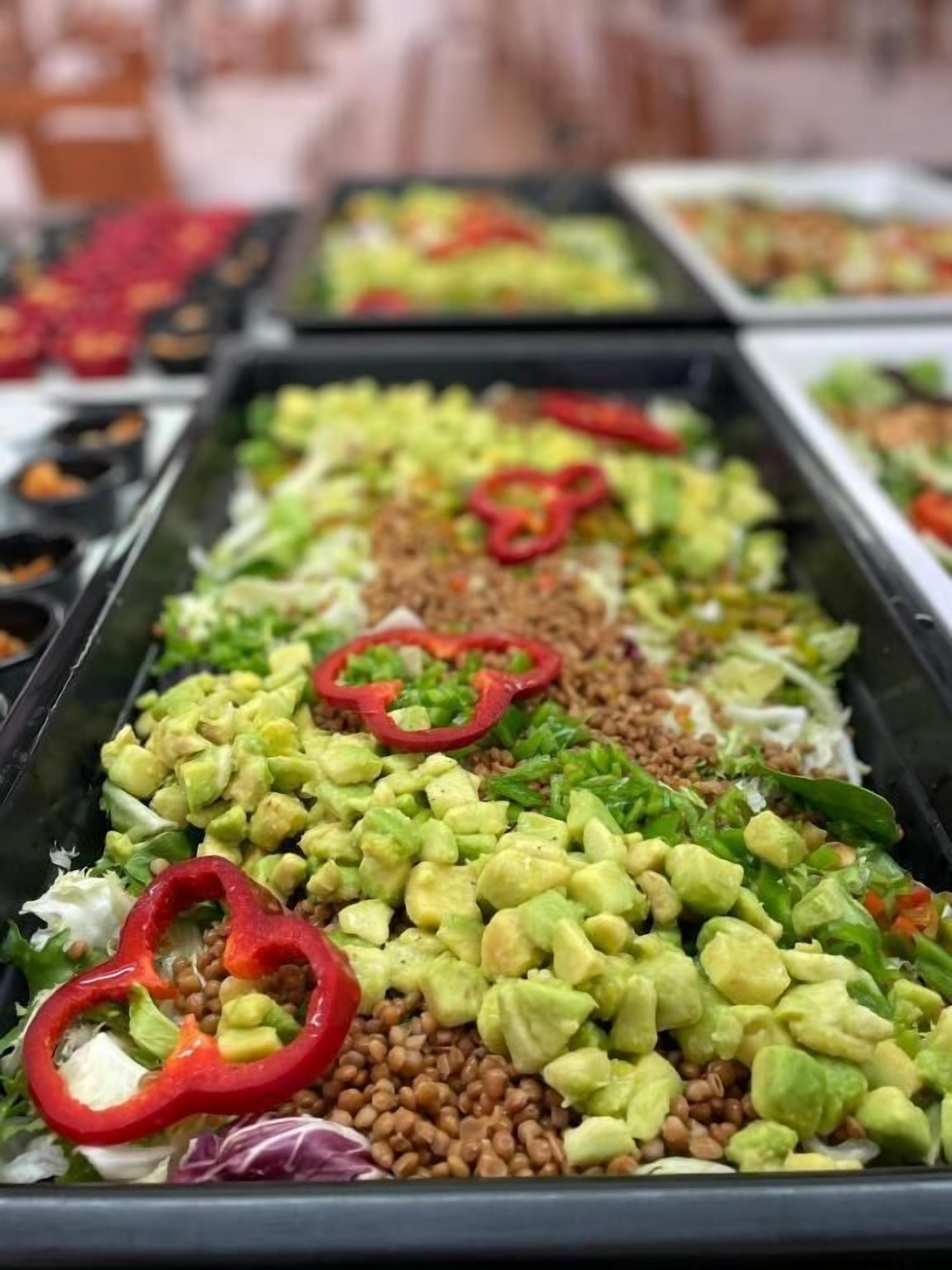 Un bufé con una variedad de platos, entre ellos ensaladas, cereales y verduras.