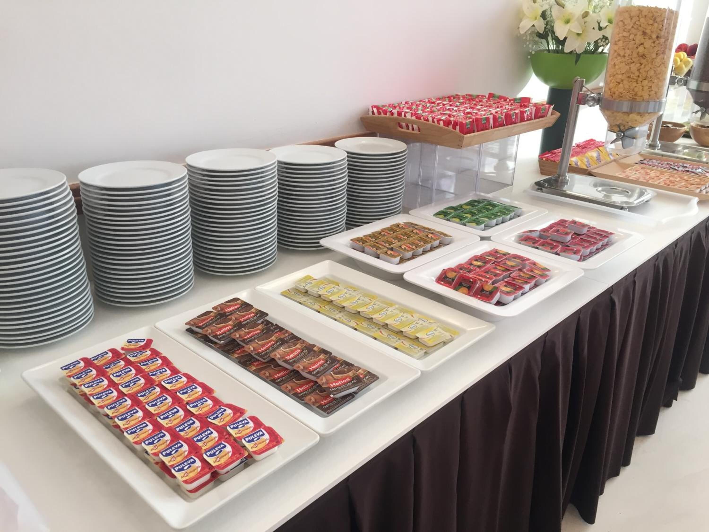 A buffet table with various food items and stacked plates.