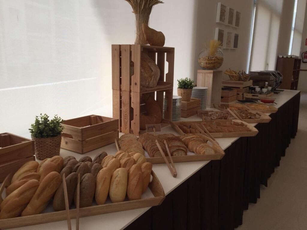 Ein Büfett mit verschiedenen Brotsorten und Backwaren, Holzkisten und einer dekorativen Vase.