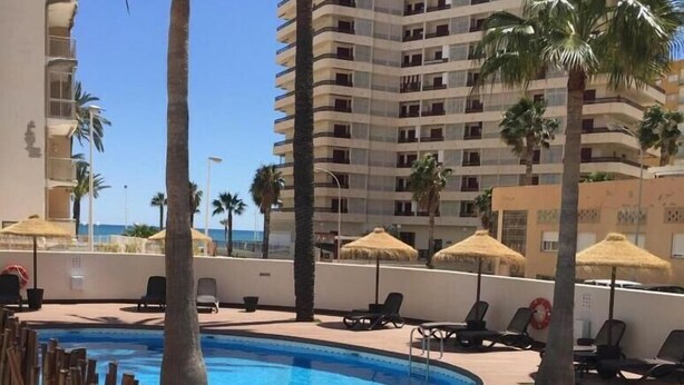 A hotel pool area with two separate pools, lounge chairs, and palm trees.