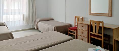 Een hotelkamer met twee eenpersoonsbedden, een bureau met stoel, een aan de muur bevestigde televisie en een grote spiegel.