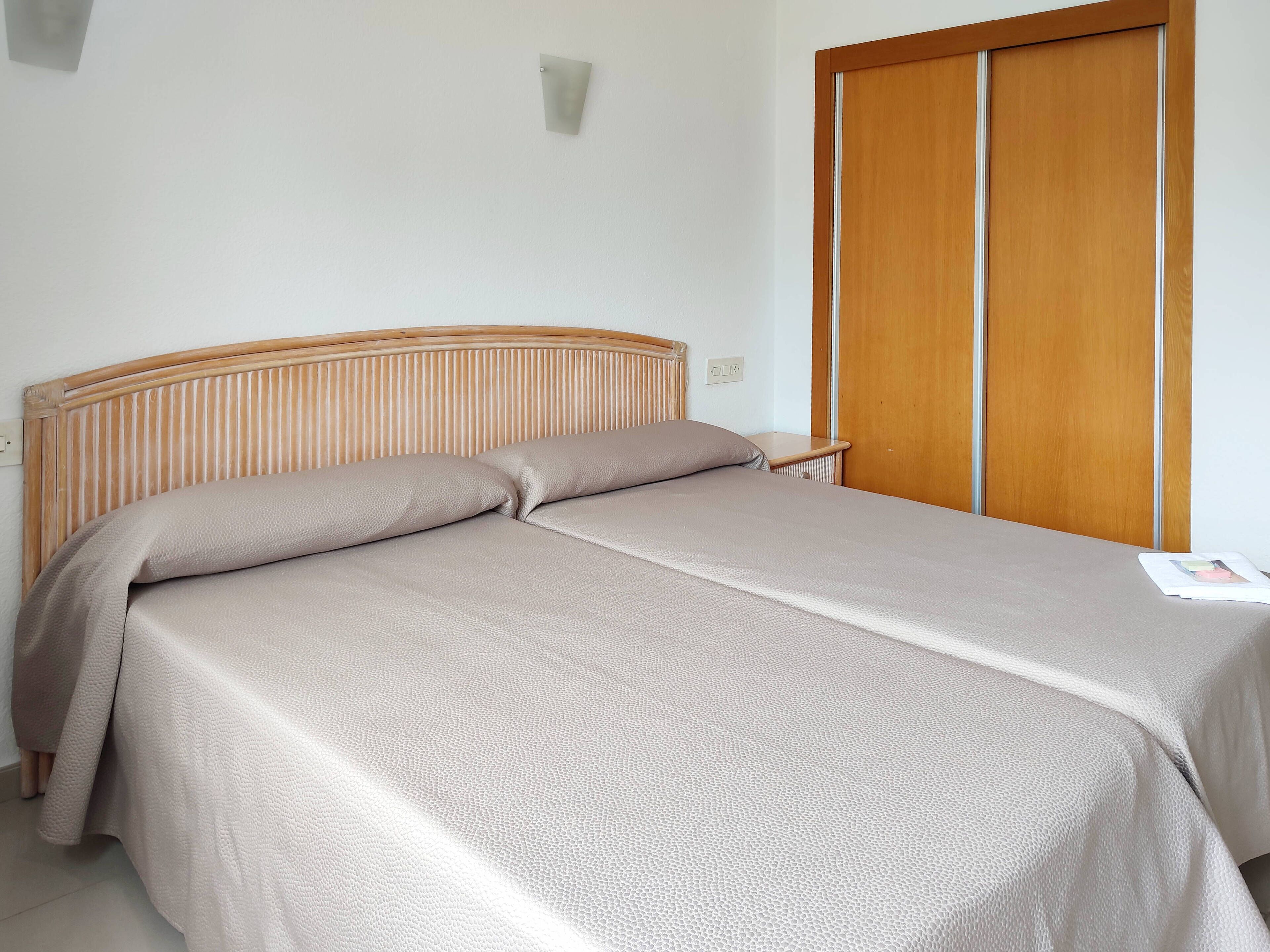 Una cama con cabecera de madera, una mesita de noche y un armario de madera.