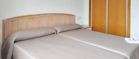 Una cama con cabecera de madera, una mesita de noche y un armario de madera.