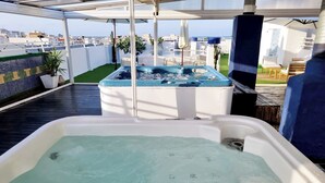 A rooftop terrace with a hot tub, outdoor seating, and a view of the cityscape. - Hotel Porto (Gandia)