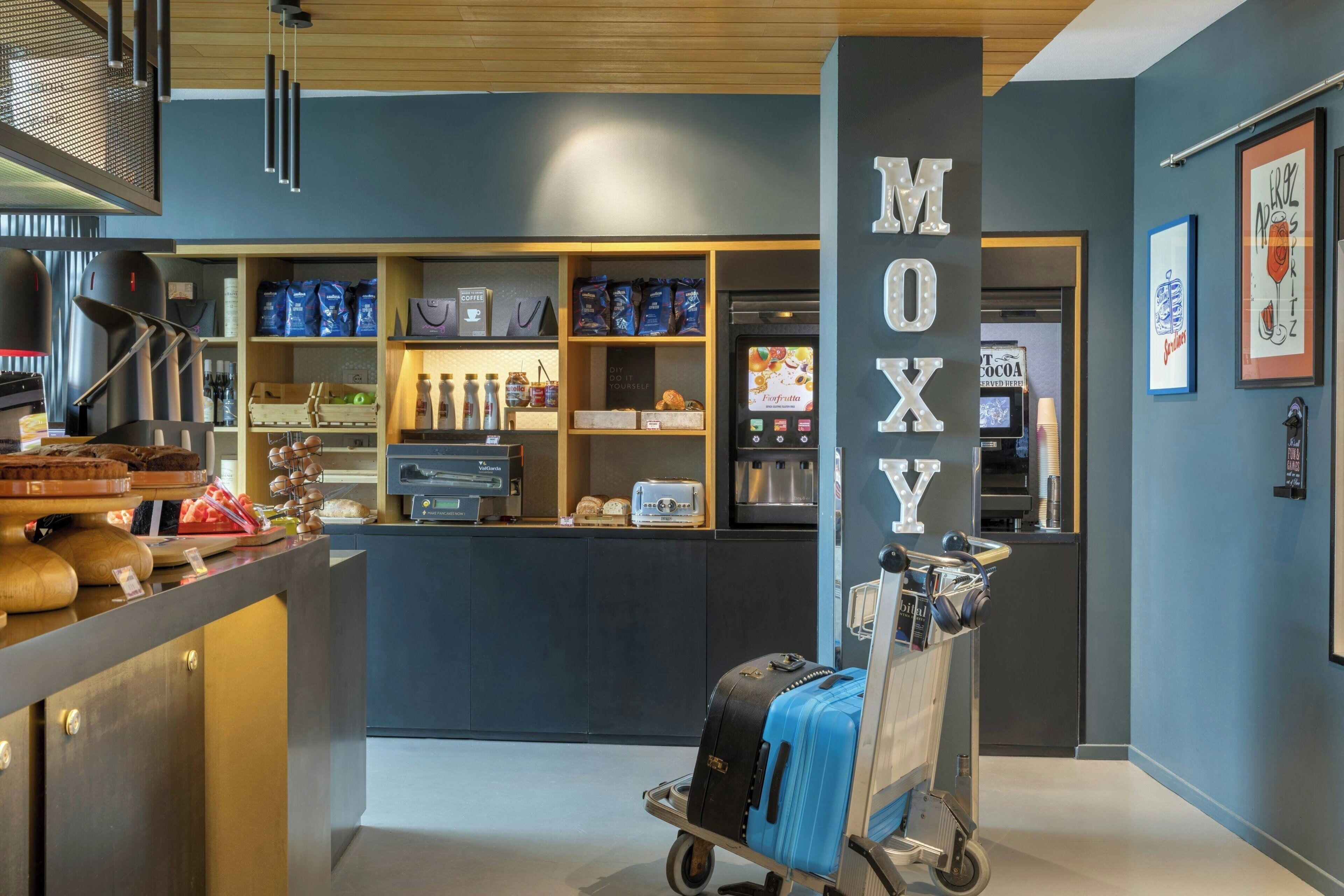 Ein modernes Café-Interieur mit einer Theke, auf der Kaffeebohnen und Gebäck ausgestellt sind, einer Kaffeemaschine und einem Gepäckwagen.