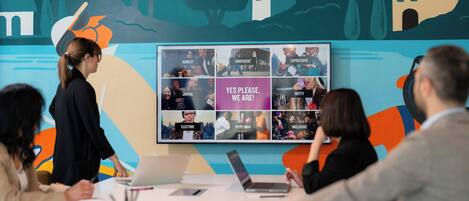 A conference room with a large display board featuring various team attributes.