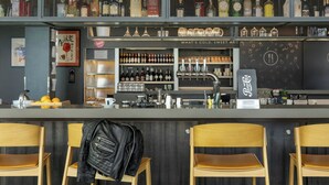 A bar area with shelves of bottles, a Pepsi sign, and wooden chairs.