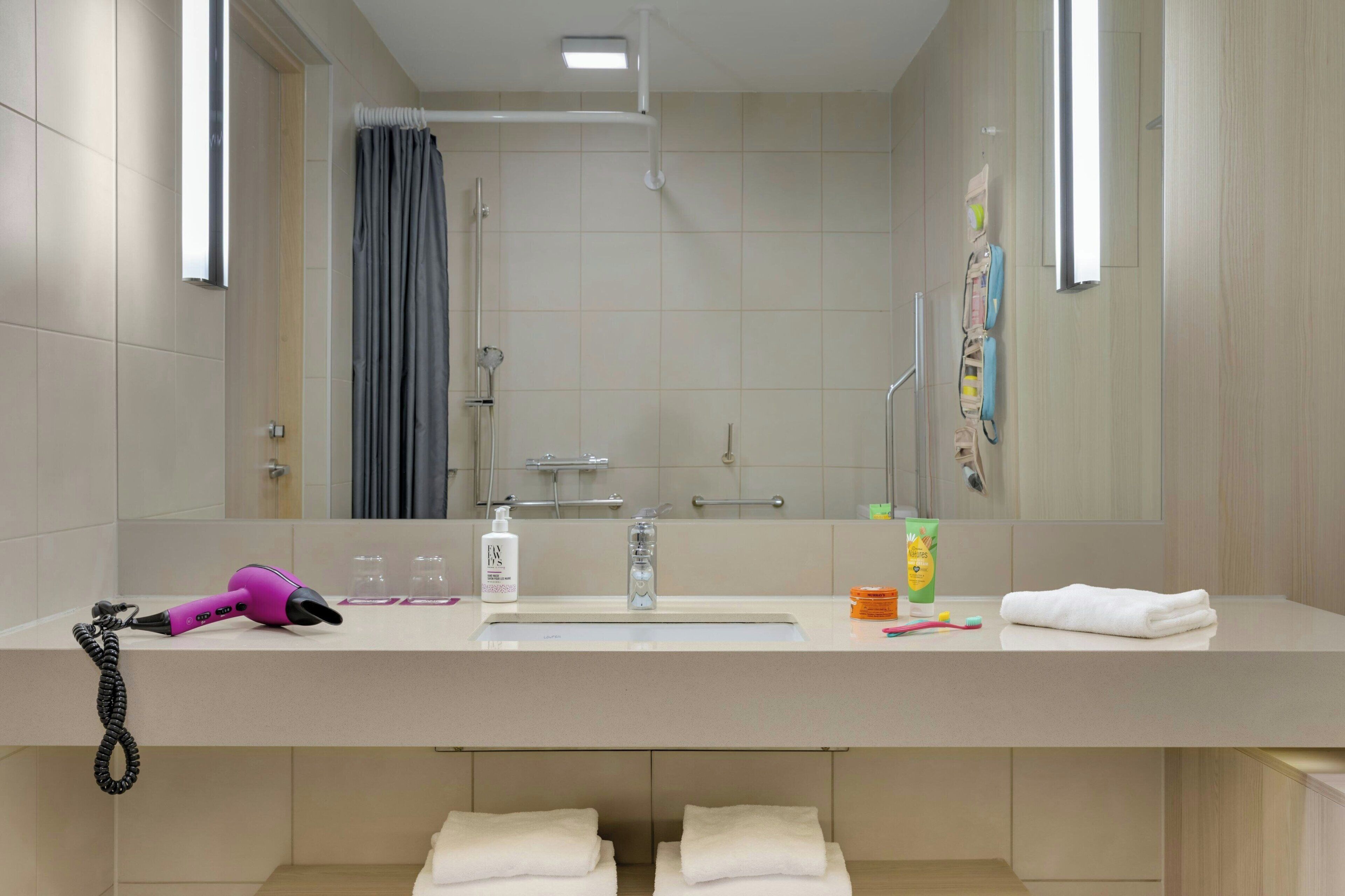 A modern bathroom with a large mirror, a sink, and a shower area.