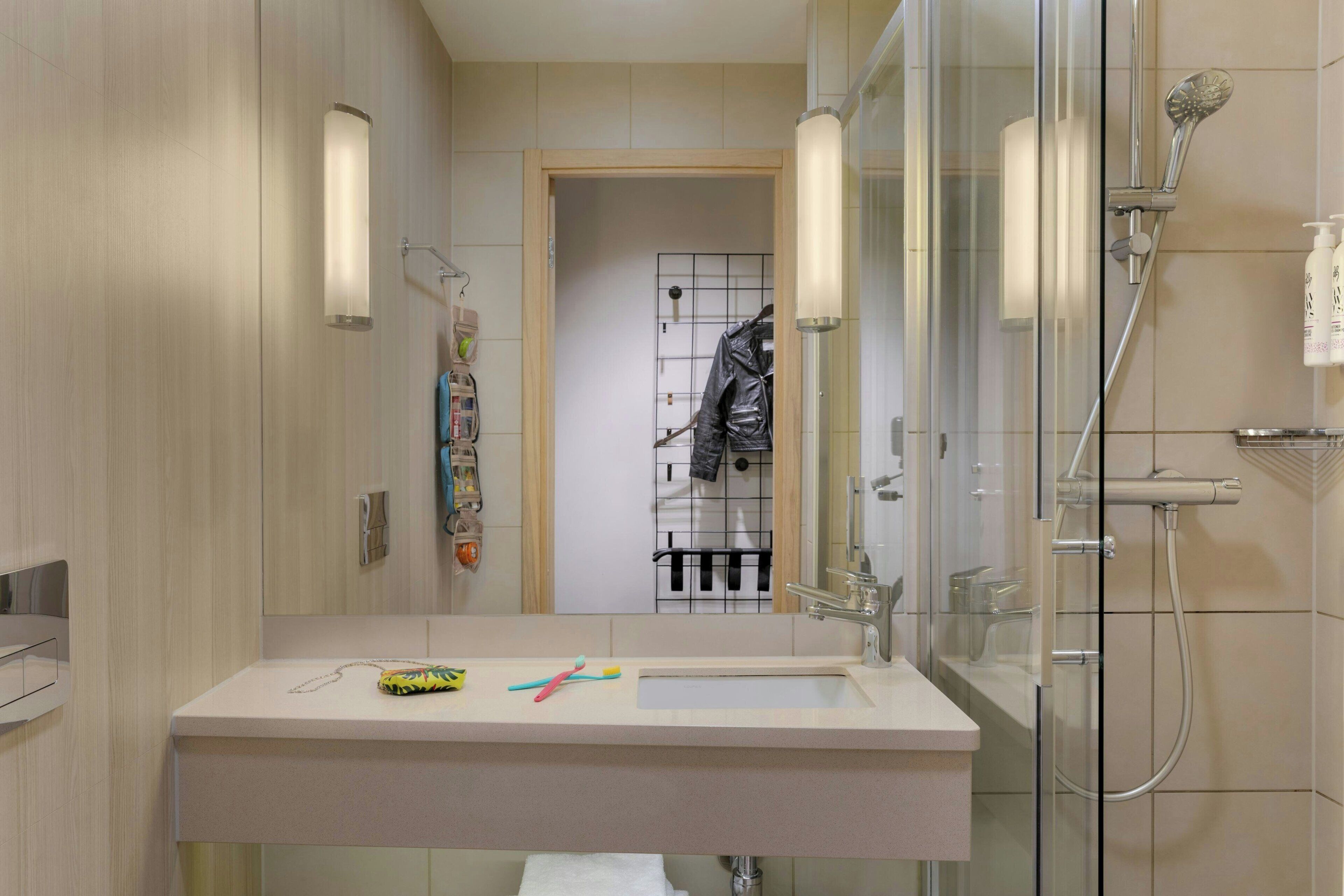Une salle de bain moderne avec une douche à parois de verre, un lavabo blanc et un miroir.