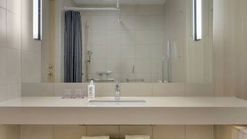 A modern bathroom with a large mirror, a sink, and a shower.