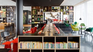 Une bibliothèque moderne dotée d’étagères, d’espaces de lecture et d’une exposition centrale de maquettes d’avions.