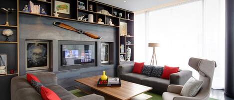 A modern living room with a grey sofa set, a wooden coffee table, and a television mounted on the wall.