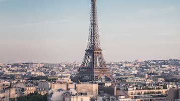 A high-angle view of the Eiffel Tower in Paris, surrounded by dense urban buildings and trees.
