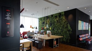Un espace de bureau moderne avec un bureau en bois, plusieurs ordinateurs et un mur végétal agrémenté de plantes suspendues.