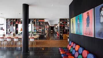A modern library with bookshelves, a dining area, and colorful stools.