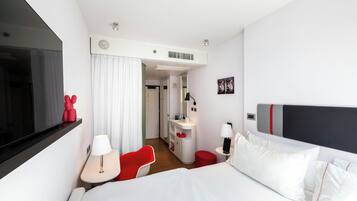 Une chambre d’hôtel moderne équipée d’un grand lit, d’un bureau, d’une chaise et d’un téléviseur.