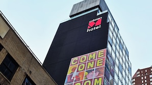 A tall building with a 'Citizen Hotel' sign and a 'Come One Come All' mural on its facade.