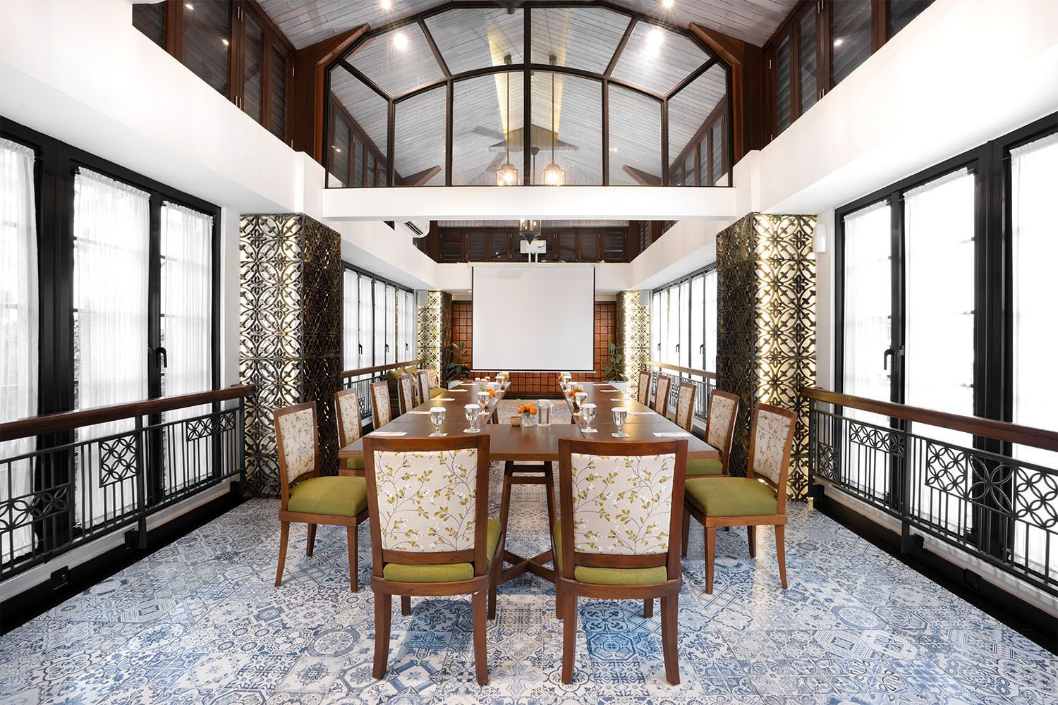 A conference room with a long table, chairs, a projector screen, and patterned walls.