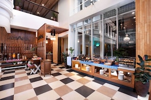 A hotel lobby with a checkered floor, wooden furniture, a buffet counter, and large windows. - THE 1O1 Yogyakarta Tugu (Yogyakarta)