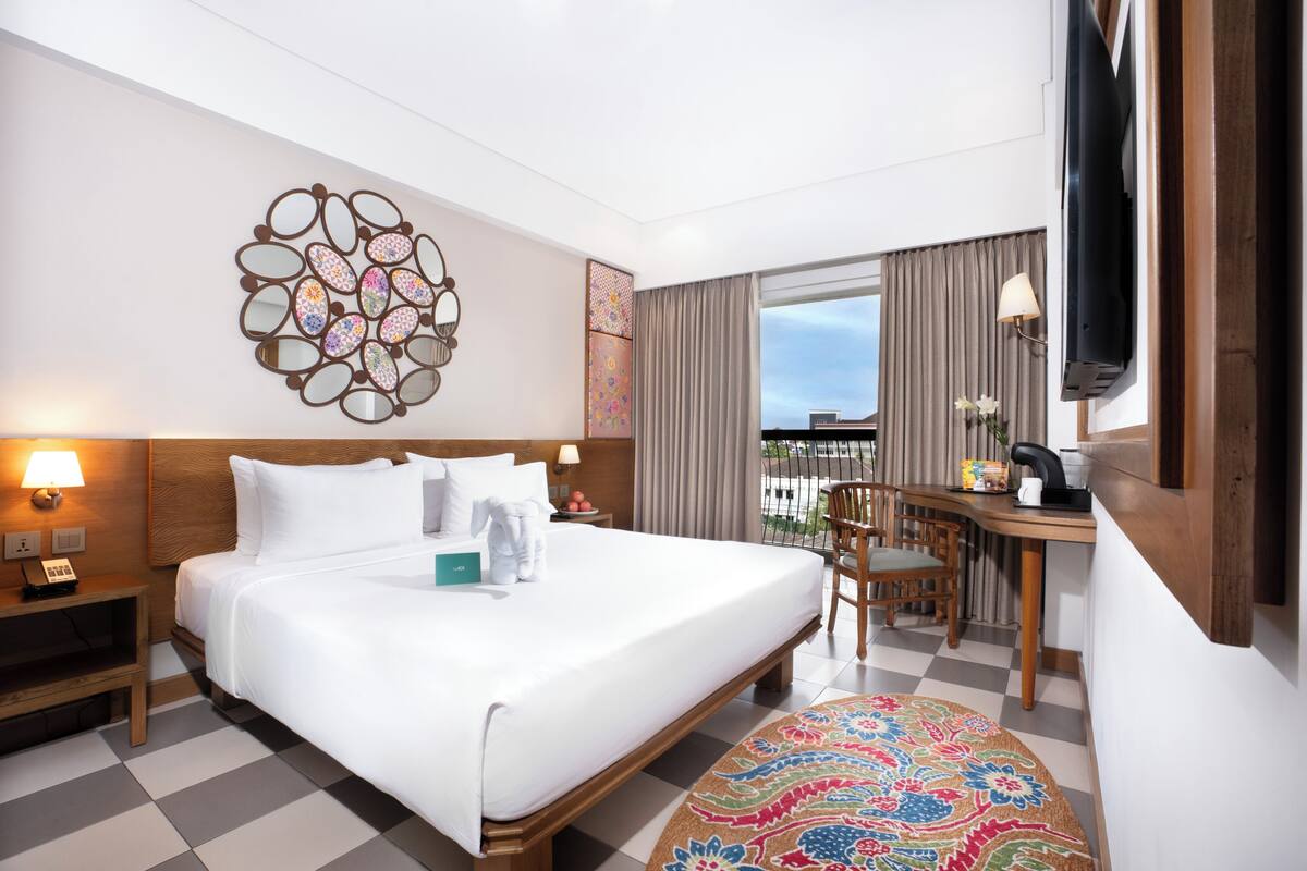 A hotel room with a bed, a desk, a chair, a television, and a view of the outdoors.