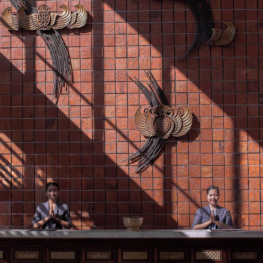 A reception desk with a tiled wall featuring decorative patterns and two winged figures.
