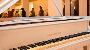 Un piano de cola en un espacio interior bien iluminado, posiblemente el vestíbulo de un hotel o un área para eventos.