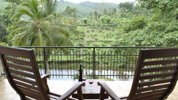 Enjoy a romantic evening on this balcony overlooking a serene landscape with a river and palm trees.