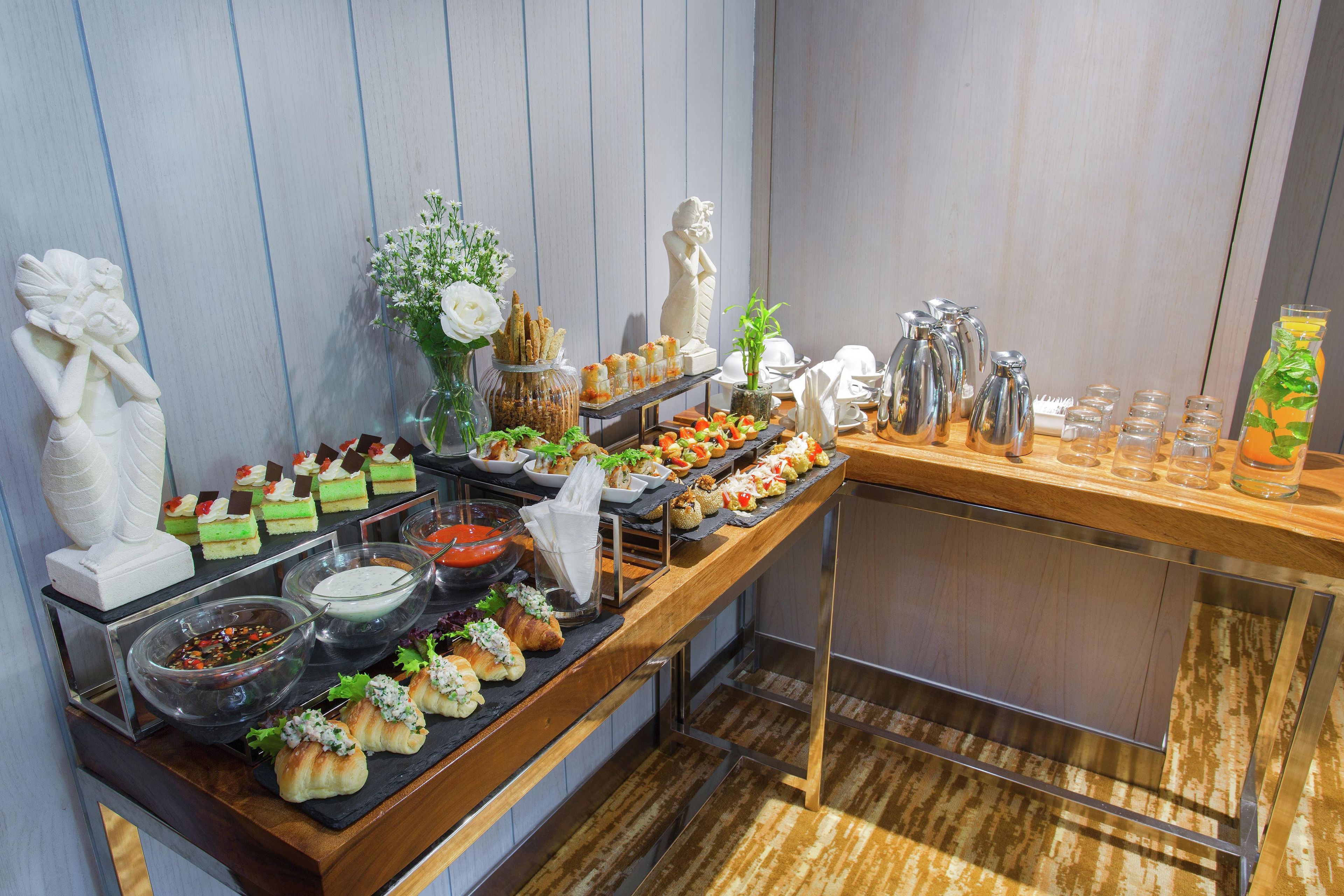 A buffet with various food items and beverages, including pastries, salads, and a selection of drinks.