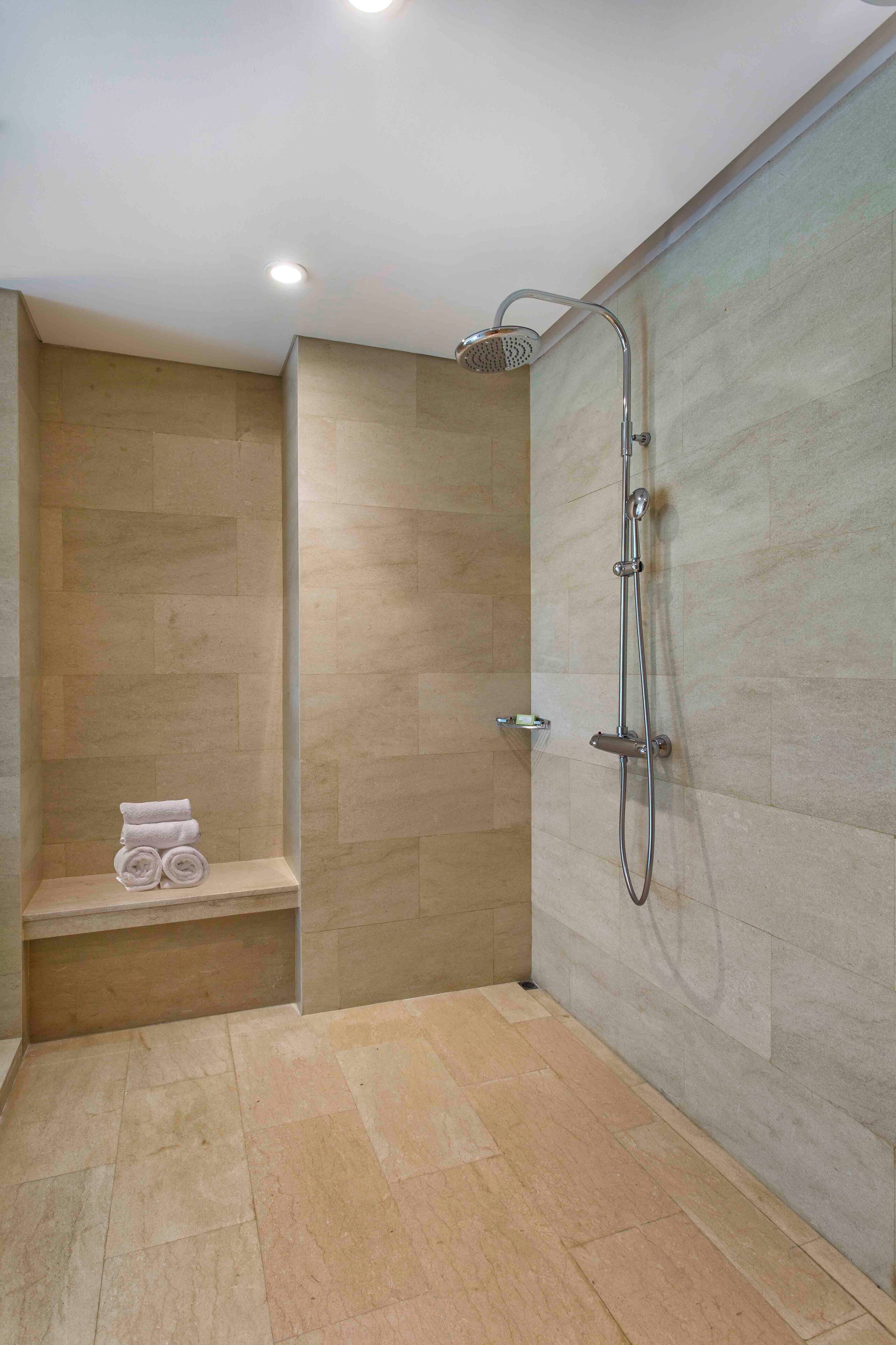 A modern shower with a handheld showerhead and a wall-mounted faucet.
