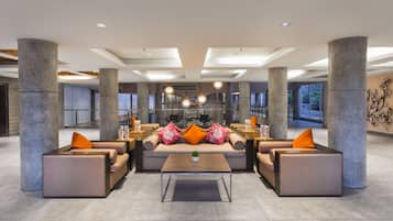 A spacious lobby with modern furniture, large pillars, and a central seating area.
