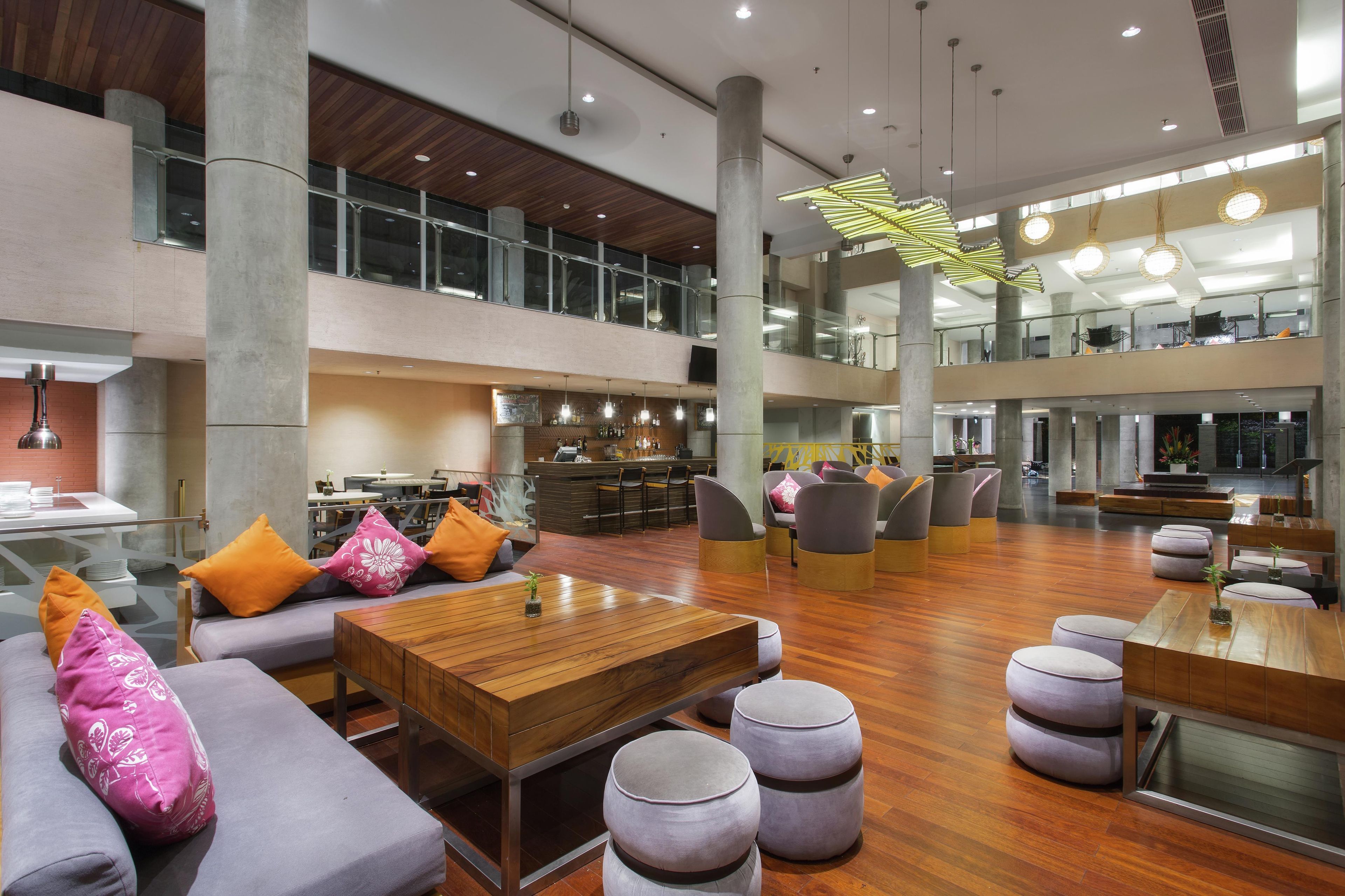 A spacious lobby with a bar area, seating arrangements, and a high ceiling with modern lighting fixtures.