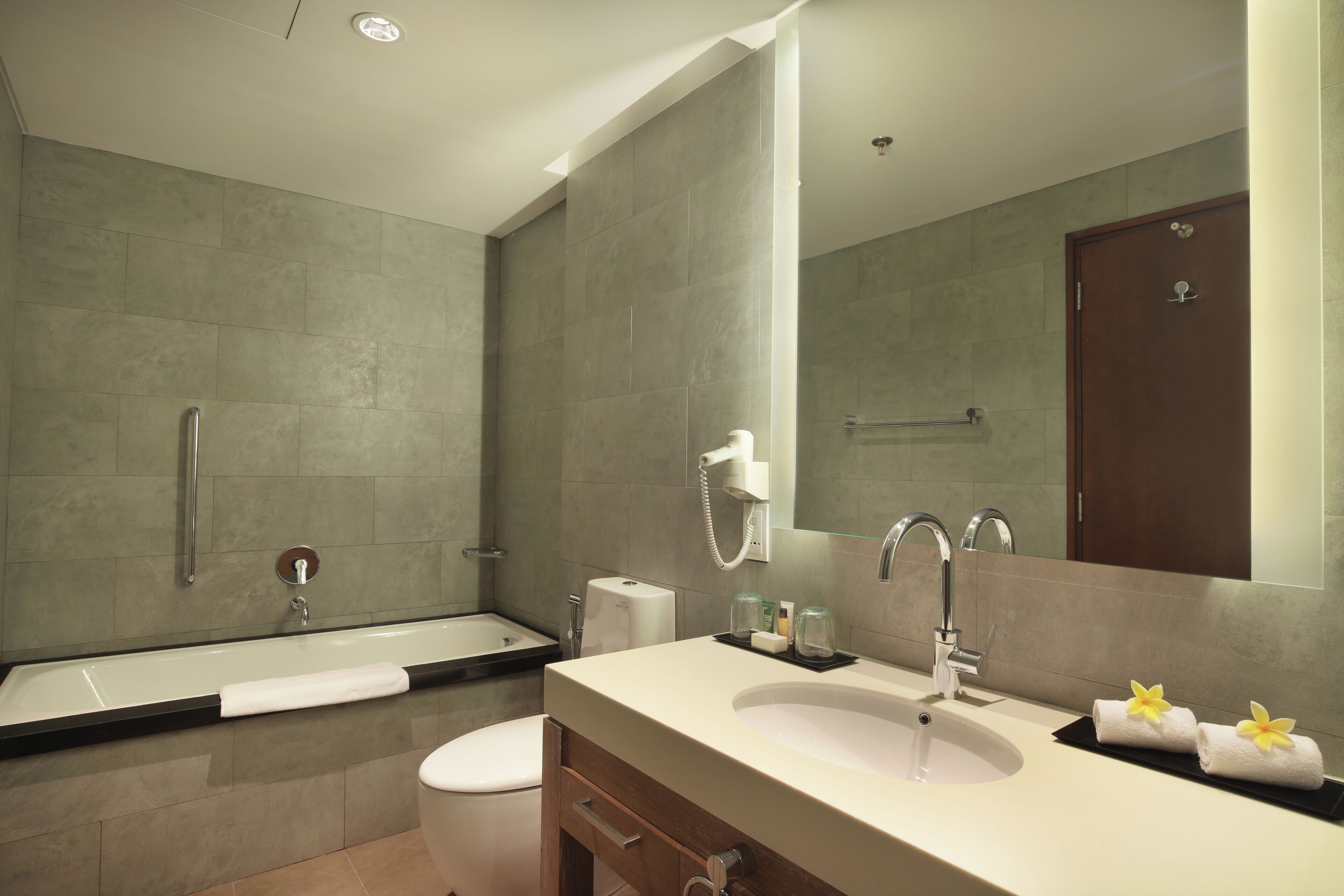 Ein modernes Badezimmer mit Badewanne, Toilette, Waschbecken und einem großen Spiegel.