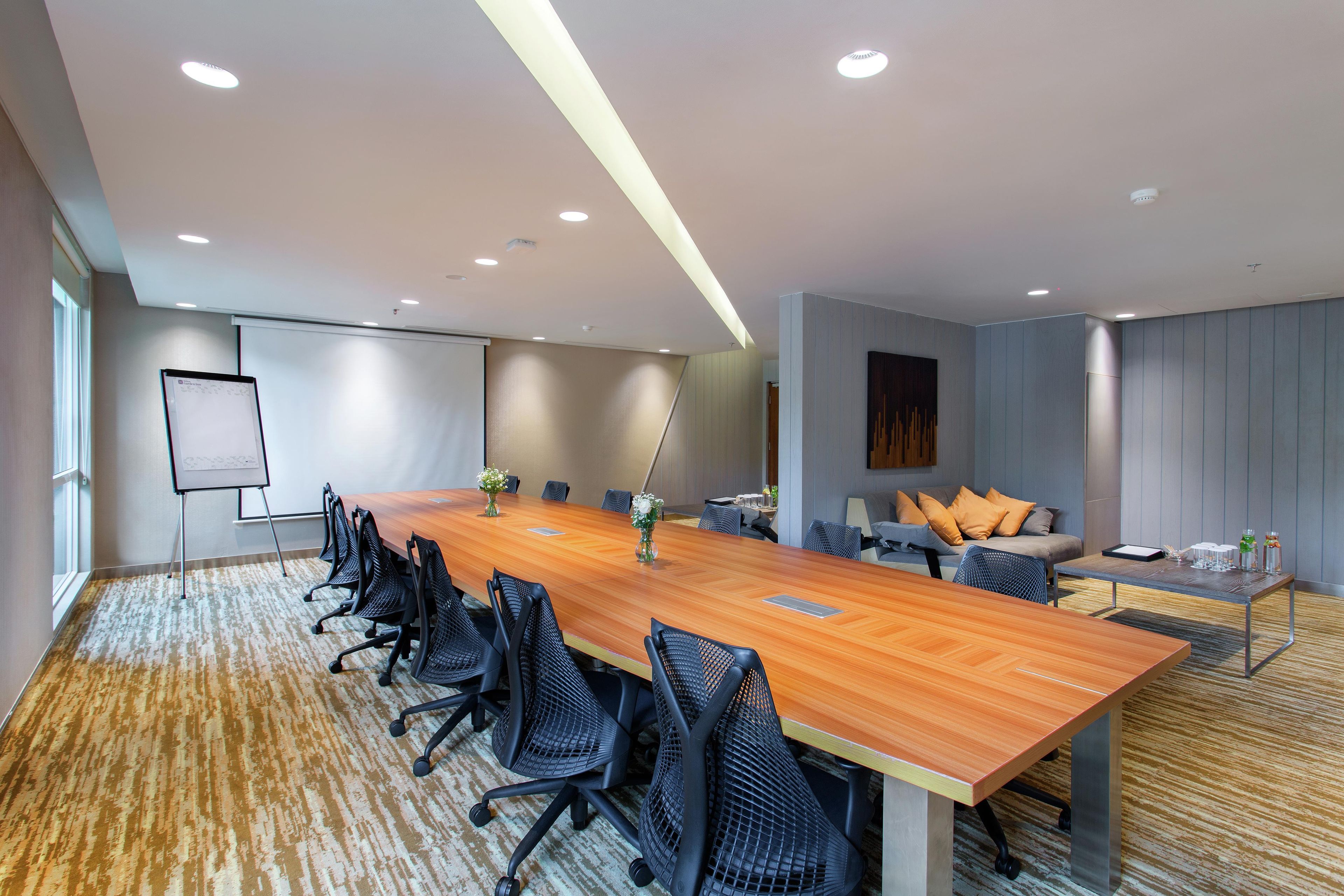 A conference room with a long table, chairs, a whiteboard, and a sofa with cushions.