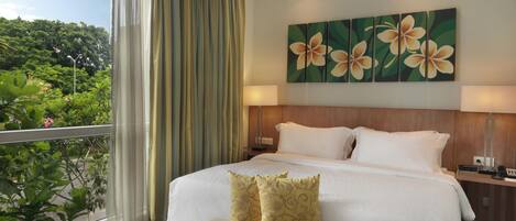 A hotel room with a large bed, a bench, a nightstand, and a painting of flowers.