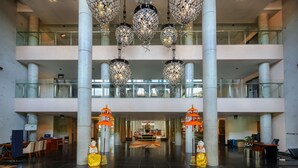 A spacious lobby with a high ceiling, multiple floors, and a central reception desk. - Hilton Garden Inn Bali Ngurah Rai Airport (Tuban)
