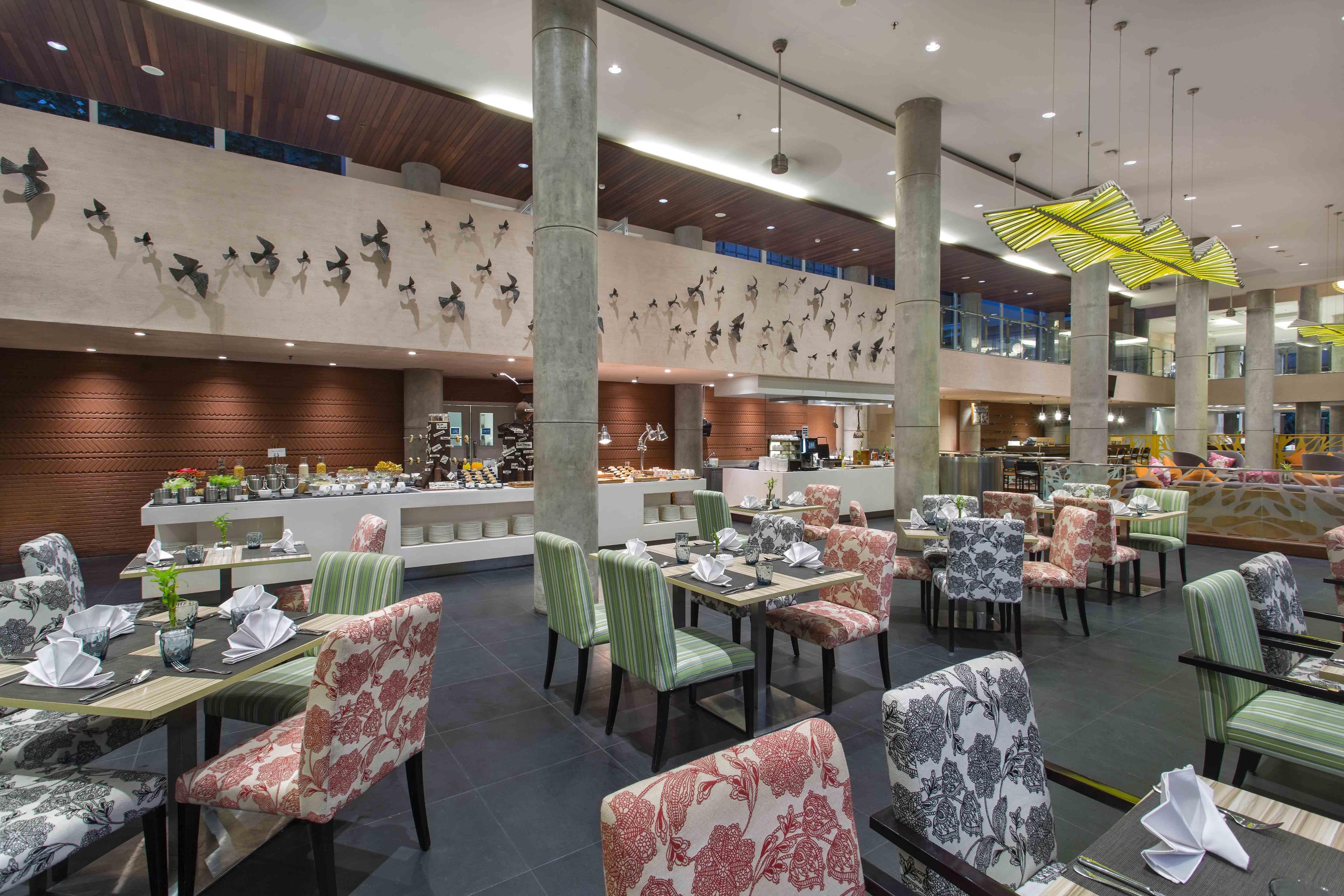 A spacious restaurant with multiple dining areas, high ceilings, and decorative wall art.