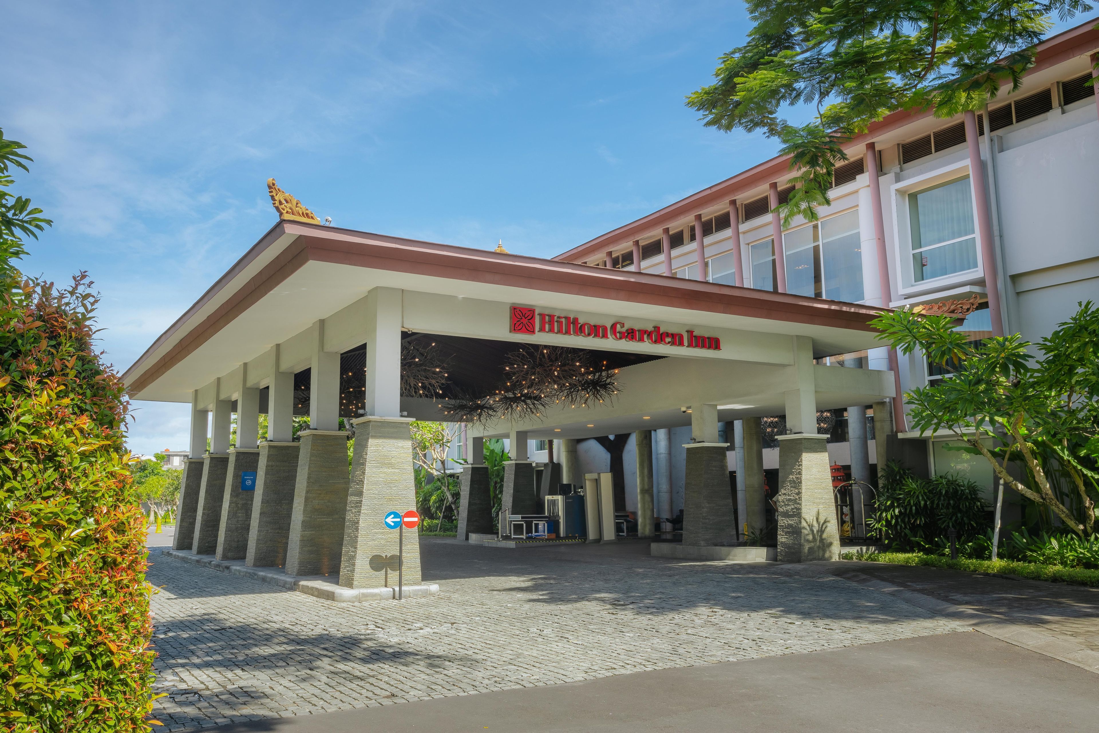 The entrance of a Hilton Garden Inn with a covered walkway and a sign above the entrance.