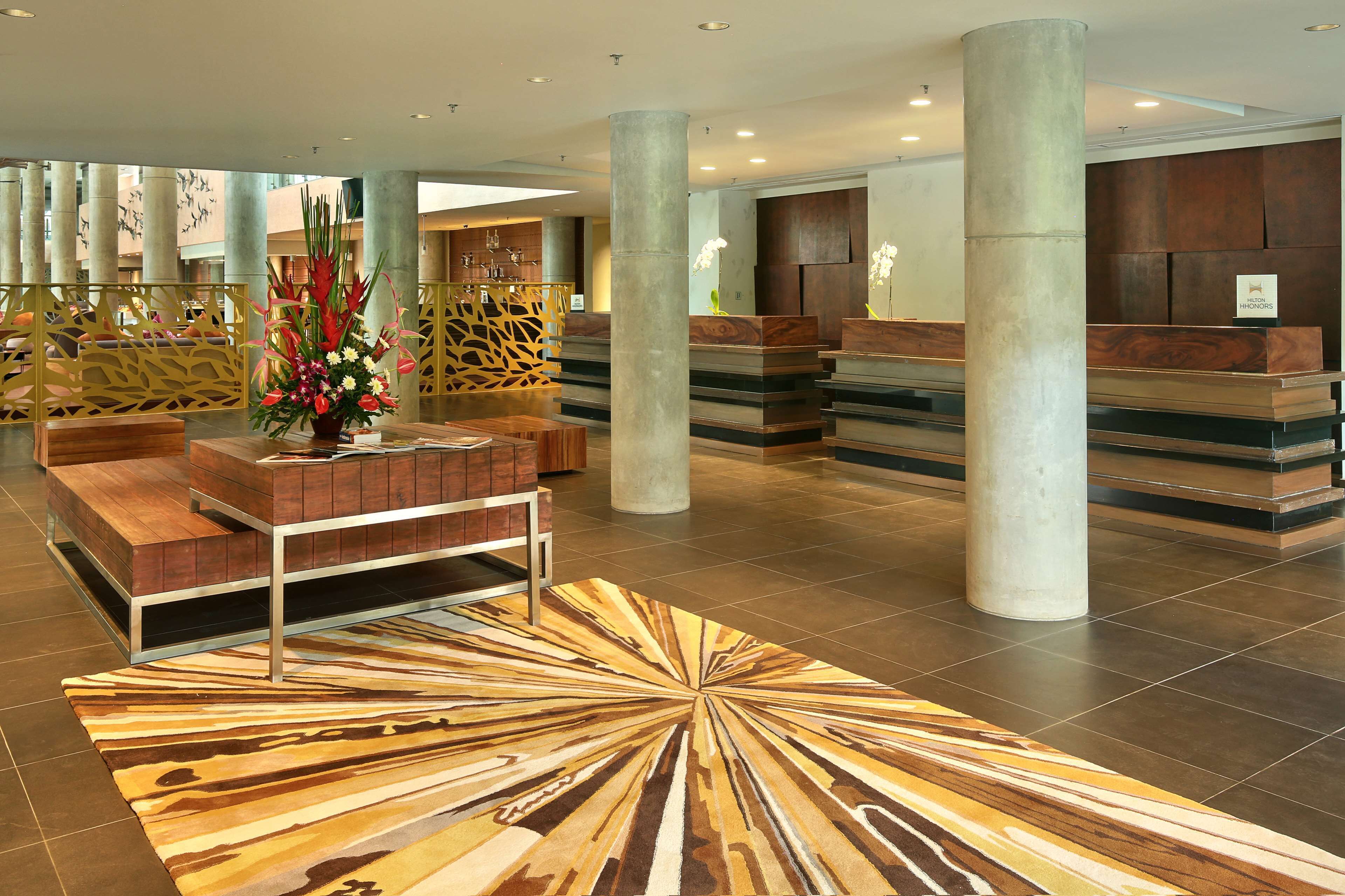 A spacious lobby with a reception desk, seating area, and a decorative rug.