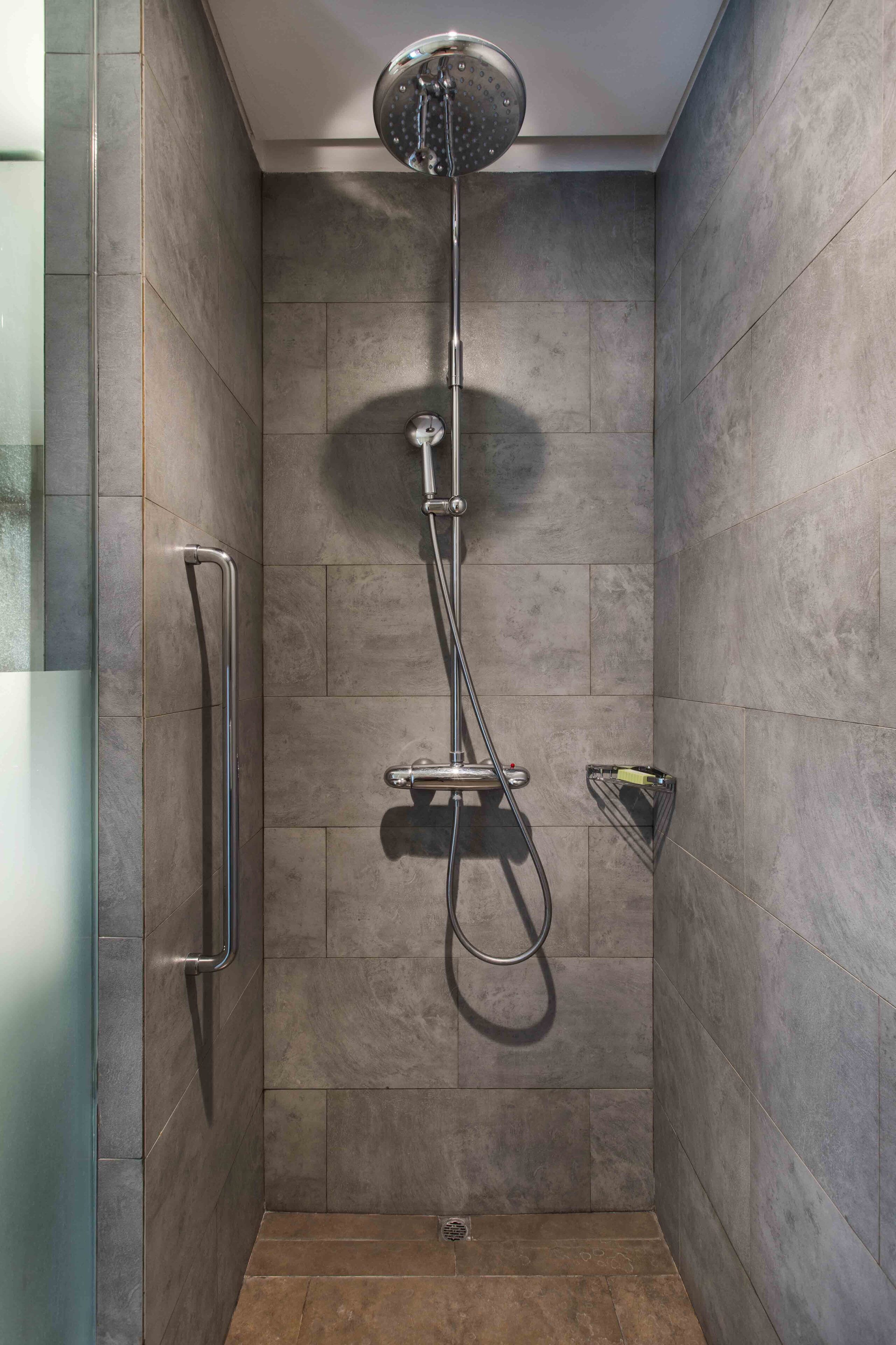 A shower with a handheld showerhead, a handheld showerhead, and a handheld showerhead.