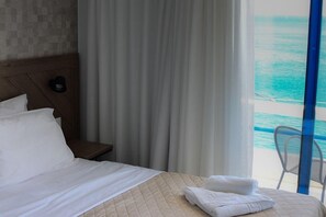 A hotel room with a bed, a nightstand, and a view of the ocean. - Kyma (Sfakia)